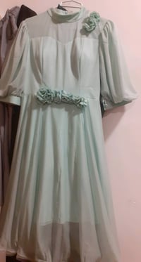 فستان سهرة أنيق بلون أخضر بارد مع تفاصيل زهور على الخصر والكتف. يتميز ...