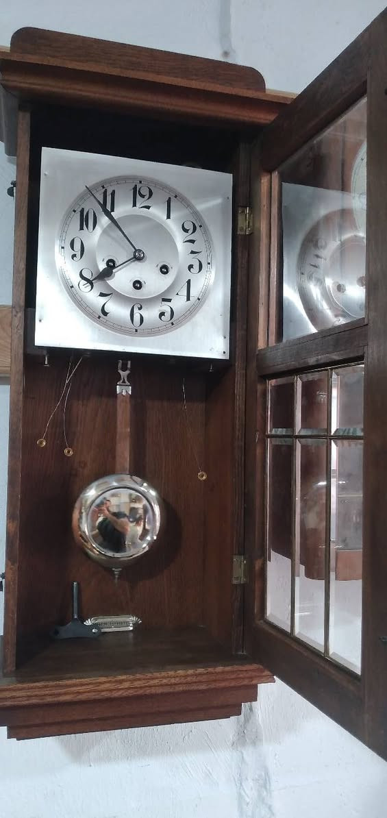 ساعة بك بن جونغ هانز (Junghans):  قطعة كلاسيكية رائعة تحمل طابعاً تاريخياً مميزاً. 
​ نوع الساعة والتصميم (الستايل)
​النوع: ساعة حائط بندولية بصندوق خشبي (Regulator Wall Clock / Box Clock).
​ بشكل واضح إلى أسلوب الآرت ديكو (Art Deco) أو المودرن الكلاسيكي الذي ساد في الفترة الممتدة بين عشرينيات وثلاثينيات القرن الماضي (1920s - 1930s).
​الخطوط الرأسية المستقيمة والزخارف الهندسية البسيطة على جانبي الهيكل الخشبي.
​الزجاج السفلي المقسم إلى مربعات ومستطيلات بإطارات معدنية (Beveled leaded glass).
​أرقام الميناء (القرص) ذات الخط العريض والمائل المميّز لتلك الحقبة.
​ بلد المنشأ والصناعة
​المنشأ  ألمانيا (Germany).
​ هذا التصميم الدقيق للصناديق الخشبية، مع الميناء الفضي ذو الثقوب الثلاثية لتعبئة الزنبرك، والزجاج المقسم في الأسفل الذي يكشف عن البندول، هو العلامة التجارية الأبرز لـ الساعات الجدارية الألمانية الصنع في فترة ما بين الحربين العالميتين. كانت ألمانيا (وتحديداً منطقة الغابة السوداء ومحيطها) المركز العالمي الأقوى لإنتاج هذا النوع من الساعات وتصديرها إلى الشرق الأوسط وأوروبا.
​ الماركة 
​  مختوم  على الماكينة النحاسية الداخلية من الخلف)، والخشب الخارجي   الماركات الألمانية العريقة 
​جونغ هانز (Junghans): وهي الماركة الأكثر انتشاراً وتفوقاً في هذا التصميم الدقيق، وتشتهر بدقة ماكيناتها وهياكلها الخشبية المتينة.
​كاينزله (Kienzle): منافس قوي جداً في تلك الحقبة ولهم تصاميم مطابقة تماماً لهذا الأسلوب.
​موبير (Mauthe) أو غوستاف بيكر (Gustav Becker): خيارات محتملة جداً لنفس الحقبة الزمنية.
​ ميكانيكية 
​ثقوب التعبئة الثلاثة (3 Winding Holes): تعني أن الساعة تحتوي على ماكينة "ربع ساعة" (Chime Clock).
​ثقب لتشغيل حركة عقارب الساعة.
​ثقب لدقات ضبط الوقت عند رأس كل ساعة.
​ثقب لدقات النغمات (غالباً نغمة ويستمينستر الشهيرة Westminster Chime) والتي تدق كل 15 دقيقة.


**إذا كنت صاحب هذا الإعلان وتريد حذفه لأي سبب، رجاءا أرسل رسالة إلى الدعم الفني**