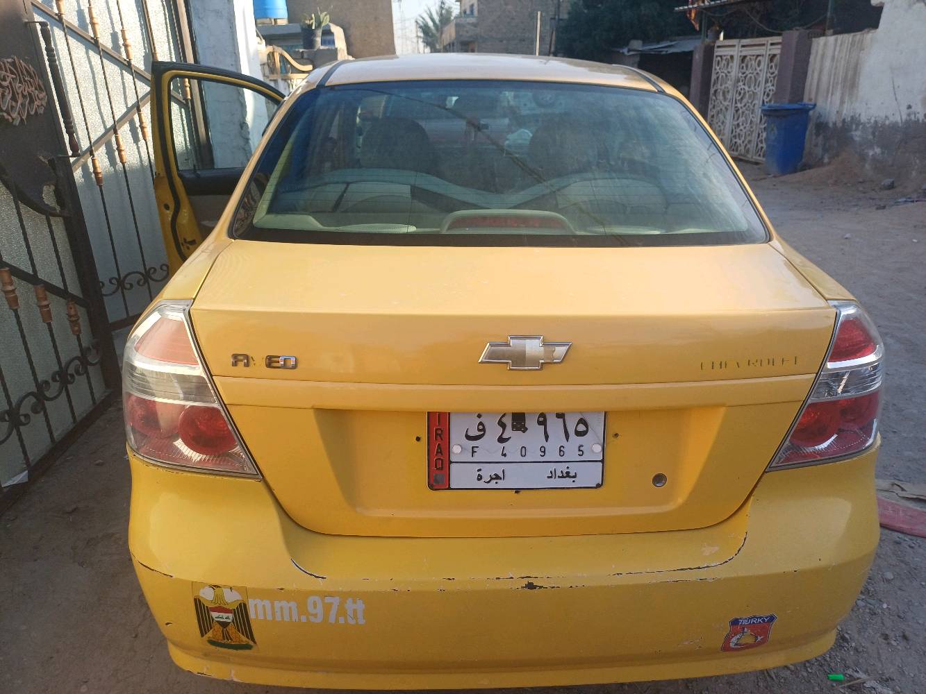سيارة شيفروليه صفراء، مناسبة للعمل كسيارة أجرة. حالتها الخارجية جيدة مع بعض الخدوش البسيطة. السيارة نظيفة من الداخل ومُجهزة بمقاعد مريحة. المكان بغداد، واللوحات تشير إلى أنها مُرخصة كسيارة أجرة.