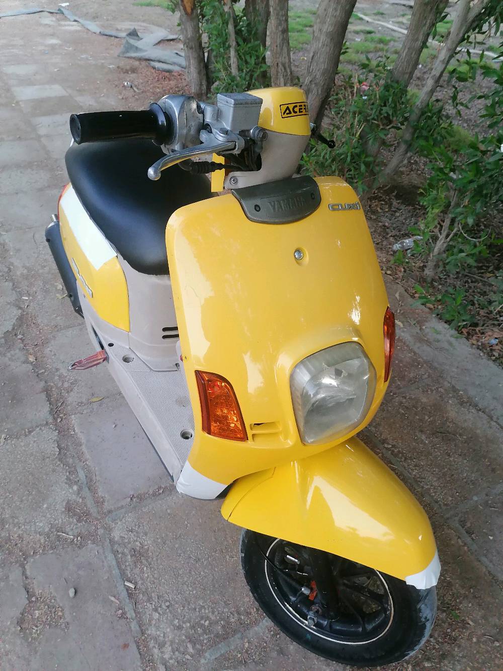 دراجة نارية نوع سكوتر لون أصفر. بحالة جيدة ومريحة للاستخدام اليومي داخل المدينة. مناسبة للتنقل السريع والاقتصادي. قليل المسافة المستهلكة نظرًا لاقتصادها في استهلاك الوقود. محرك قوي وسهل الاستخدام.