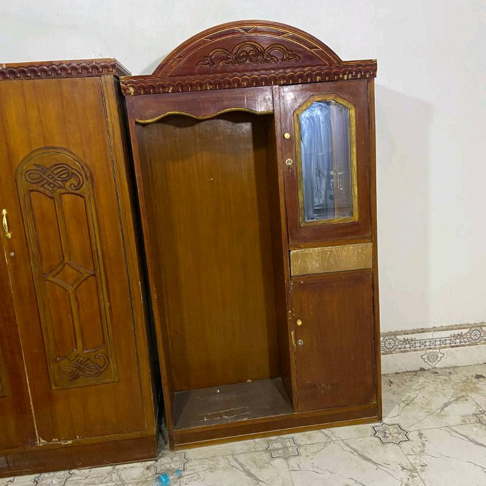 غرفة نوم خشبية كلاسيكية مكونة من سرير مع مرآة فاخرة ودولاب مكون من عدة أبواب. التصميم يحتوي على حفرات ونقوش جميلة تضيف لمسة مميزة للغرفة. الأثاث بحالة جيدة ومناسب لإضافة جمالية لأي غرفة نوم.