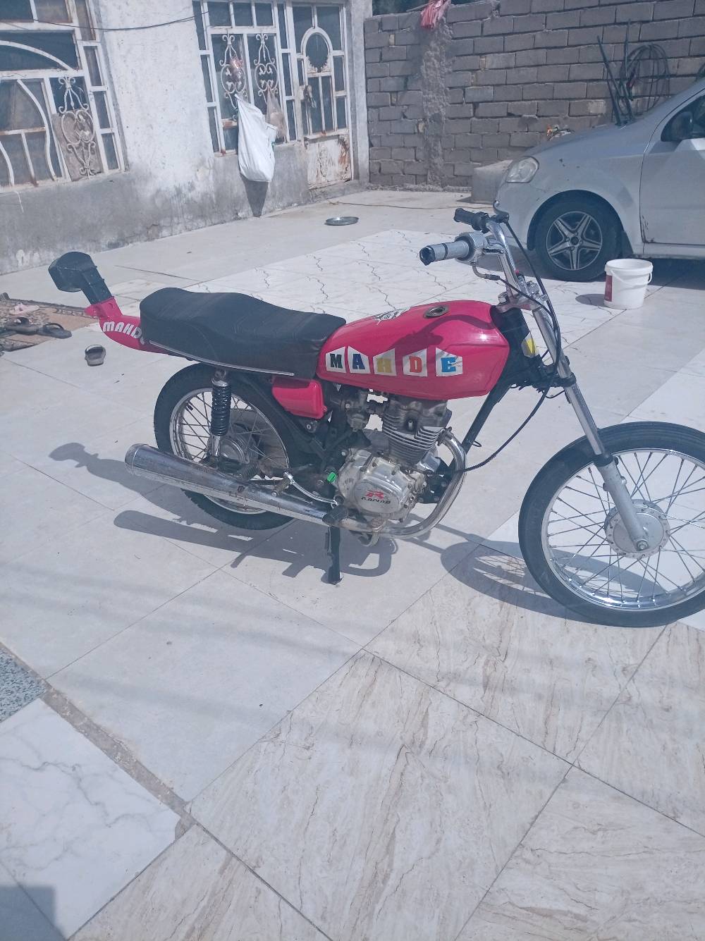 دراجة بخارية رائعة ذات لون وردي لامع ومزينة بكلمة MARDE على الجانبين. الدراجة بحالة جيدة وتعمل بسلاسة، مثالية للتنقل اليومي أو الاستعمال الشخصي. تحتوي على محرك قوي وقدرة تحمل جيدة، مما يجعلها مناسبة لمختلف أنواع الطرقات. شكلها المميز والتفاصيل الجميلة تضيف لمسة من الأناقة والتميز.