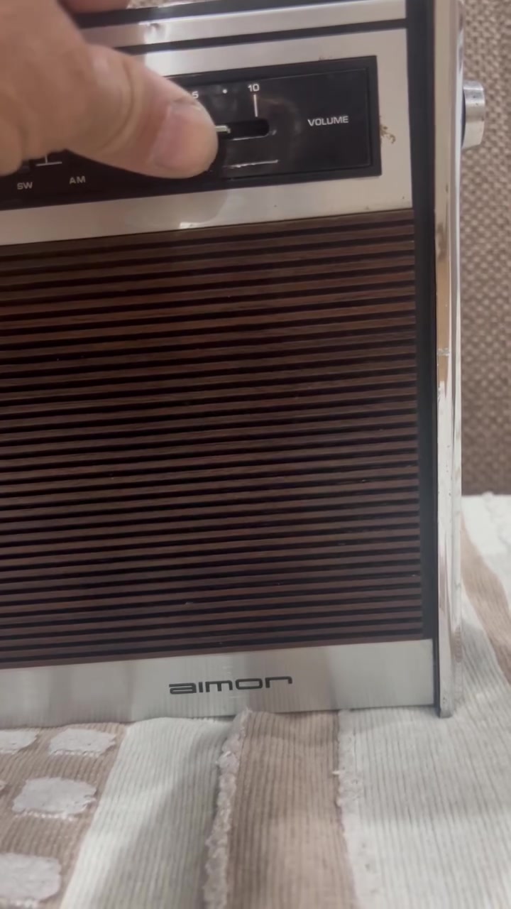 هذا جهاز راديو ومسجل كاسيت كلاسيكي مميز جداً يحمل العلامة التجارية Bimon.
إليك نظرة سريعة على تفاصيل هذا الجهاز الظاهرة في الصورة:
 المواصفات الأساسية: هو مسجل كاسيت وراديو ترانزستور عالي الثبات (Solid State) يدعم 4 موجات راديو مختلفة (4 Band) تشمل عادةً (FM, MW, LW, SW) لالتقاط الإشارات المحلية والقصيرة.
 التصميم: يتميز بالهيكل الكلاسيكي الأنيق الذي يدمج بين اللمسات المعدنية الفضية في الأعلى والأسفل، والواجهة المخططة ذات المظهر الخشبي الداكن (Woodgrain)، وهو أسلوب التصميم الذي كان سائداً ومحبوباً جداً في فترة السبعينيات وأوائل الثمانينيات.
 عناصر التحكم: يحتوي في الجزء العلوي على المفاتيح الميكانيكية التقليدية (Piano Keys) للتحكم بالمسجل (تشغيل، تقديم، إرجاع، إيقاف/إخراج)، بالإضافة إلى مؤشر صغير للإشارة وضبط الصوت والموجات على الجانب الأيمن.
هل للبيع نظيف جدا  ***********

